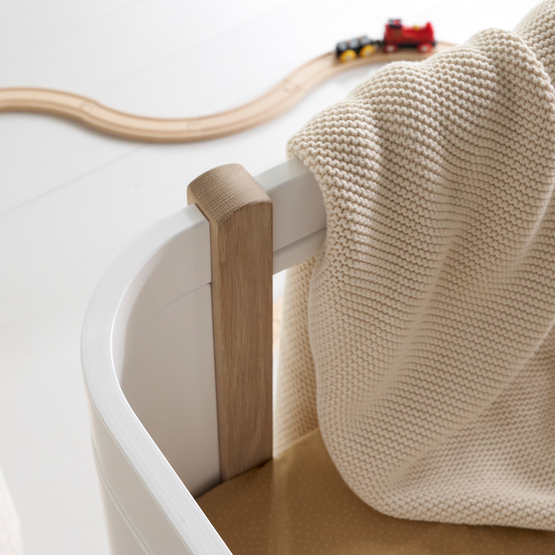 Children's toy train set on a white surface with a wooden track and a beige blanket.