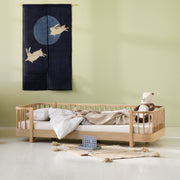 Children's bedroom with a wooden bed, teddy bear, and decorative wall hanging.
