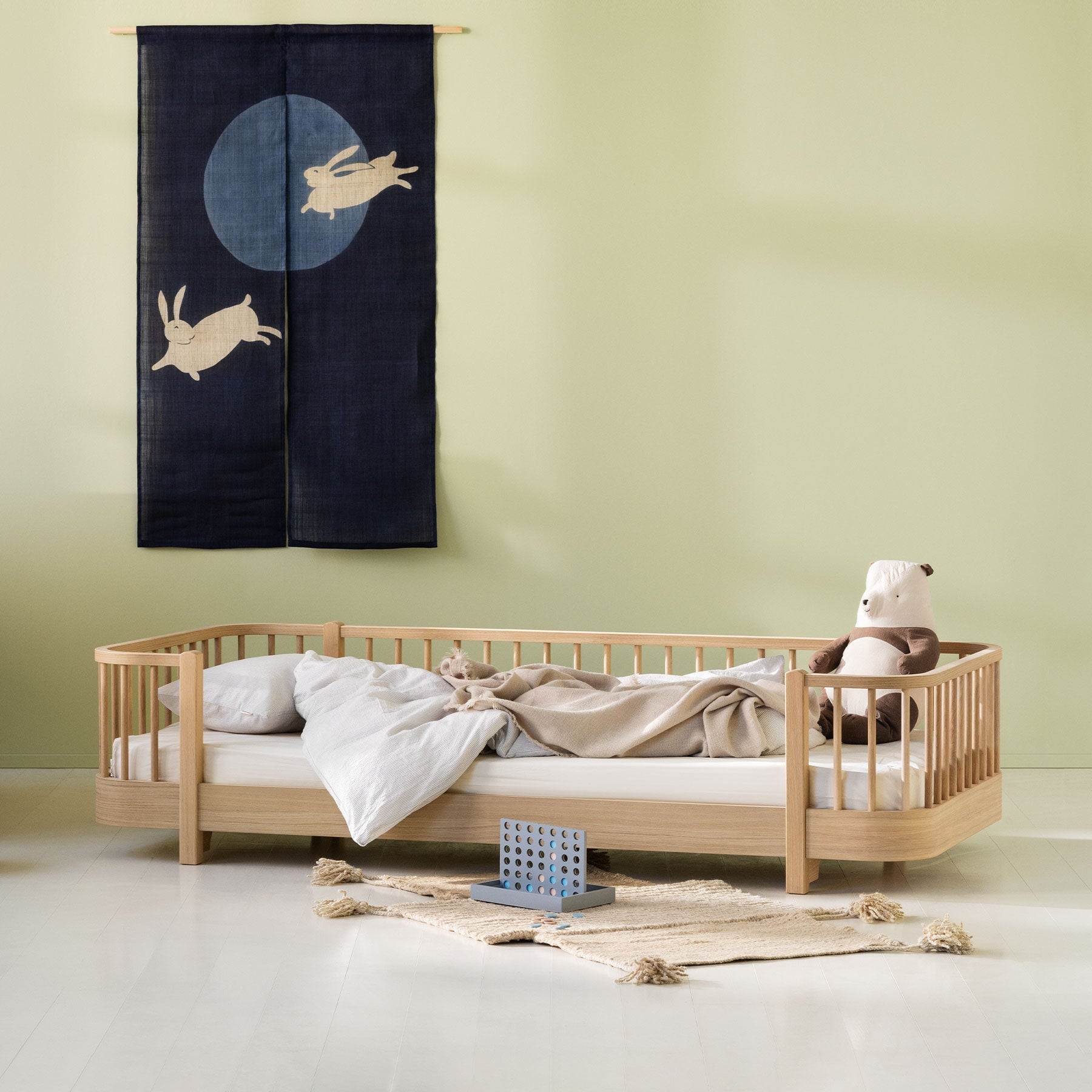 Children's bedroom with a wooden bed, teddy bear, and decorative wall hanging.