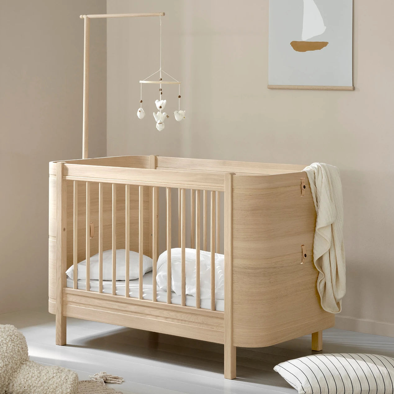 Wooden cot in a nursery with a mobile hanging above it.