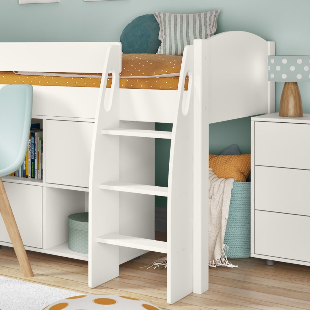 White loft bed with desk and shelves in a room with colorful pillows and a lamp.
